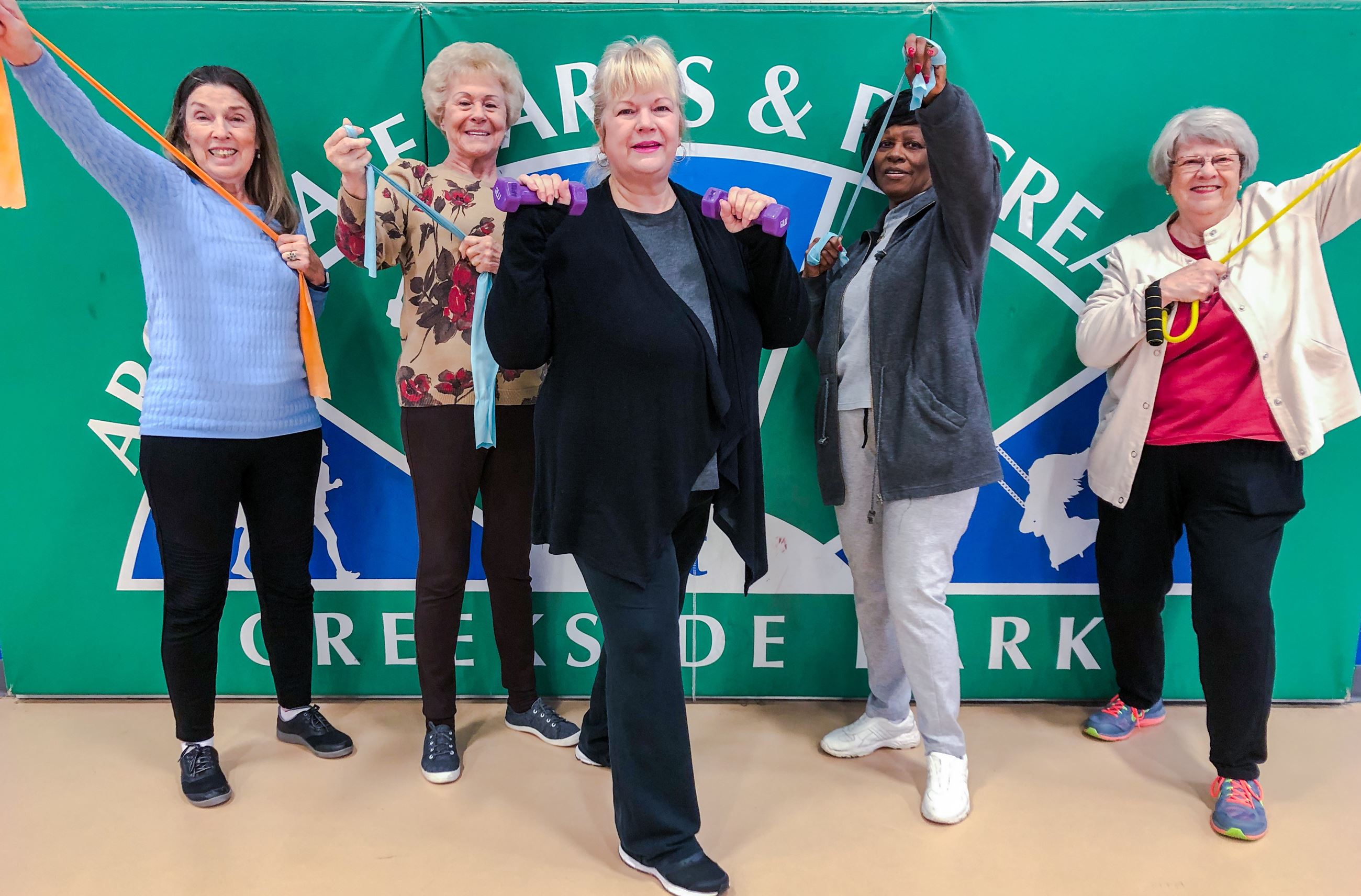 4 senior ladies and their instructor posing with bands and weights
